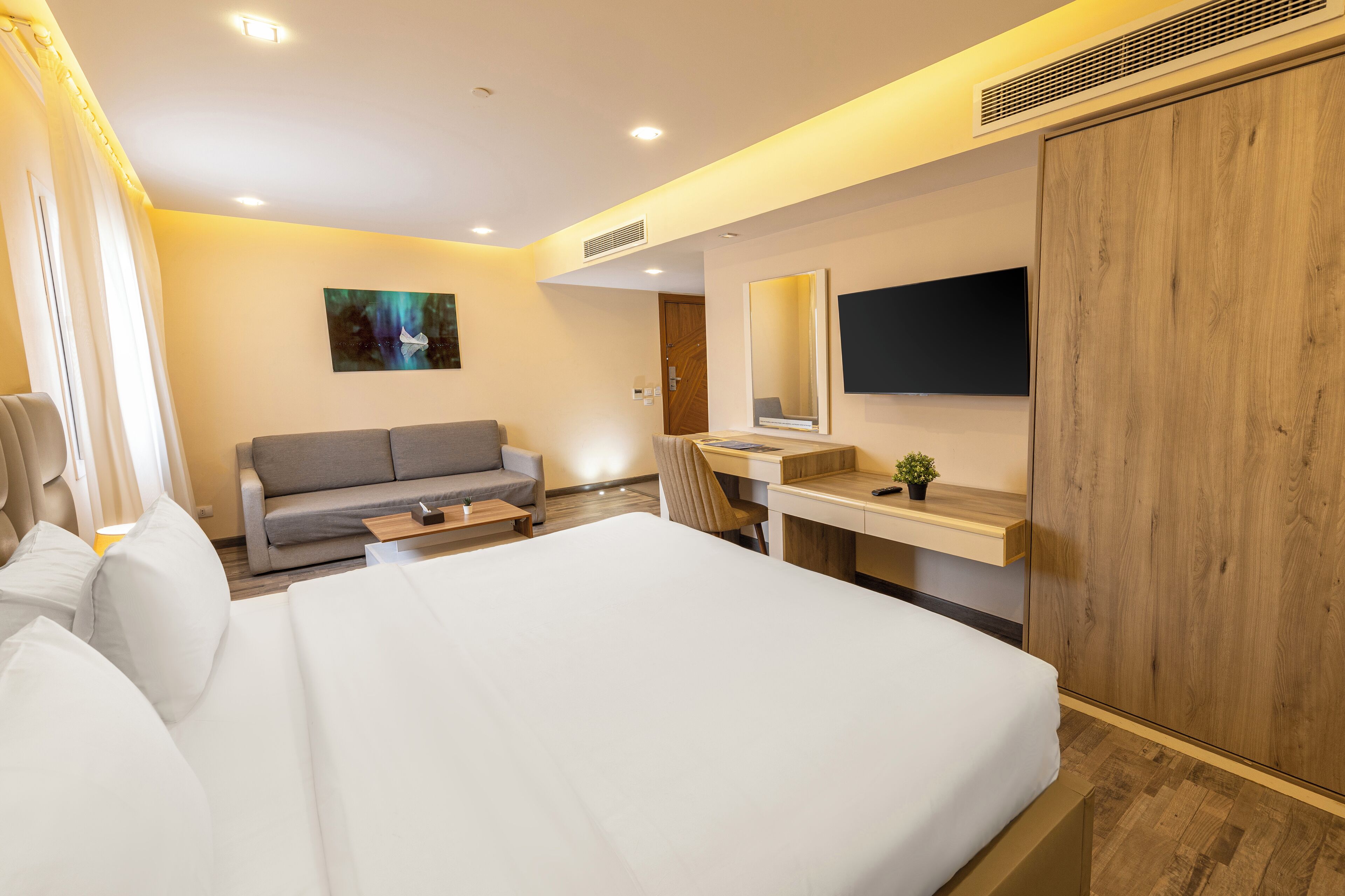 Een moderne hotelkamer met een groot bed, een bank, een bureau en een kledingkast.