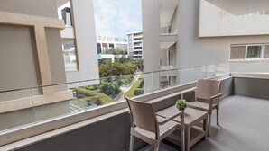 A balcony with a glass railing, two wicker chairs, and a small table with a plant. - Ocean Blue Studios (Cairo)