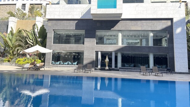 A modern hotel with a pool, large windows, and outdoor seating. - Ocean Blue Studios (Cairo)