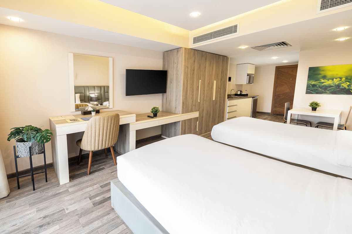 Habitación de hotel moderna con cama, escritorio, silla, televisión y kitchenette.