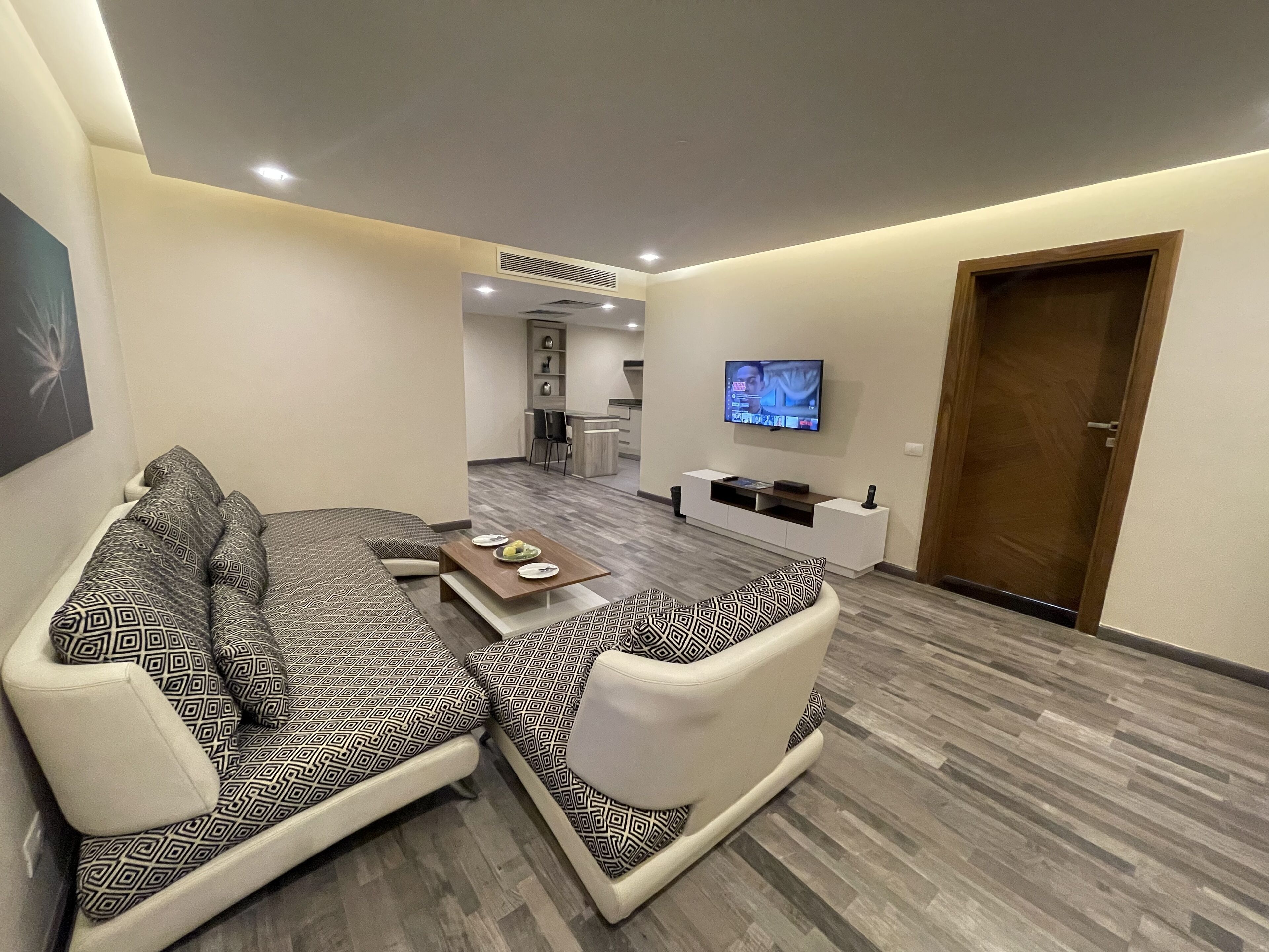 Una sala de estar moderna con un sofá, una mesa de centro y un televisor de pantalla plana montado en la pared.