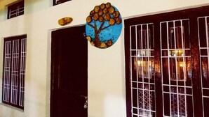 A building with a black door, barred windows, and a circular artwork with a tree and fruits.