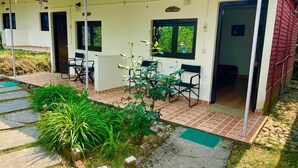 A covered outdoor area with a patio, seating, and a small garden.