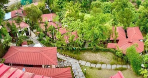 A residential area with multiple houses featuring red roofs, surrounded by lush greenery and a stone pathway.