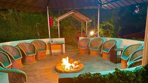 An outdoor seating area with wicker chairs and a central fire feature.