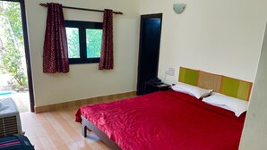 A bedroom with a large bed, a nightstand, a wall-mounted lamp, and a window with curtains.