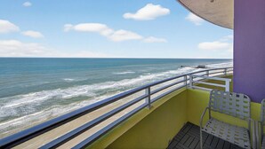 Un balcón con vista al océano, un muelle a lo lejos y una silla.