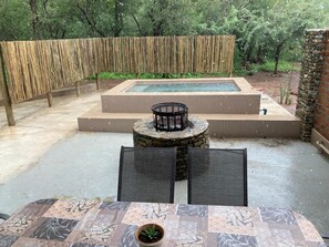 Relax in a serene outdoor space with a hot tub, surrounded by lush greenery and a seating area.