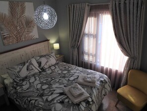 Relax in a stylish room with a large bed, armchair, and artwork featuring a leaf design.