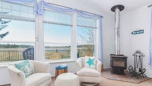 A cozy room with a large window, a fireplace, and two armchairs.