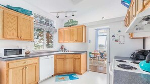 A modern kitchen with wooden cabinets, a microwave, stove, and a view of the outdoors.