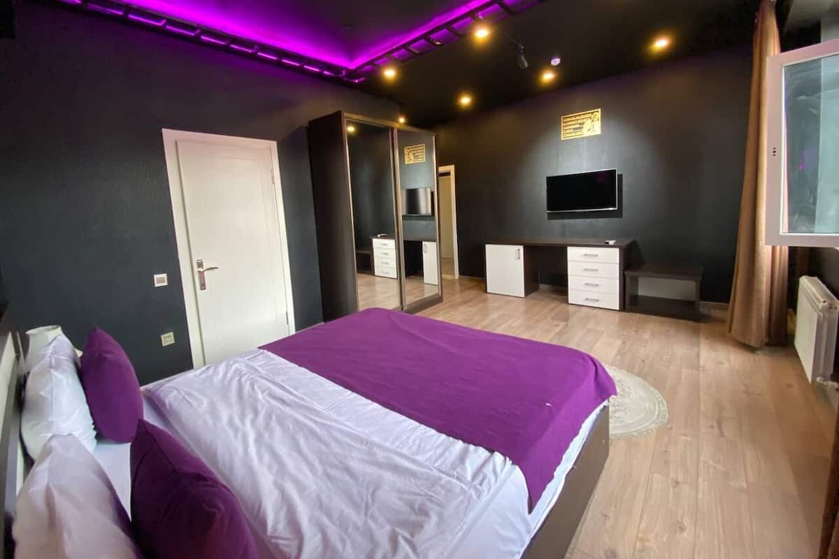 Une chambre à coucher moderne, équipée d’un lit, d’une armoire, d’un bureau et d’un téléviseur.