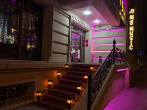A staircase with red carpet and wall-mounted lanterns, leading to a room with a large window and a neon sign reading "MY MUSIC". - My Music Hotel (Baku)
