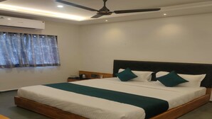 A modern hotel room with a large bed, wooden headboard, and a ceiling fan. - Hotel Fun Imperial Morbi (Morbi)