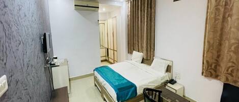 Una habitación de hotel con cama, escritorio, silla y sofá.