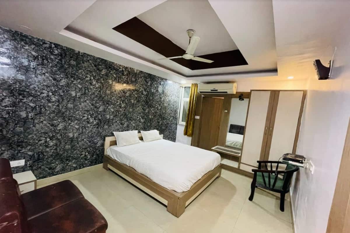 A bedroom with a bed, a wooden bench, a ceiling fan, and a marble wall.