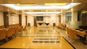 A spacious hotel lobby with a central reception desk, multiple seating areas, and a modern design featuring a reflective floor and ceiling lights. - SKG Royal Palace (Bhopal)