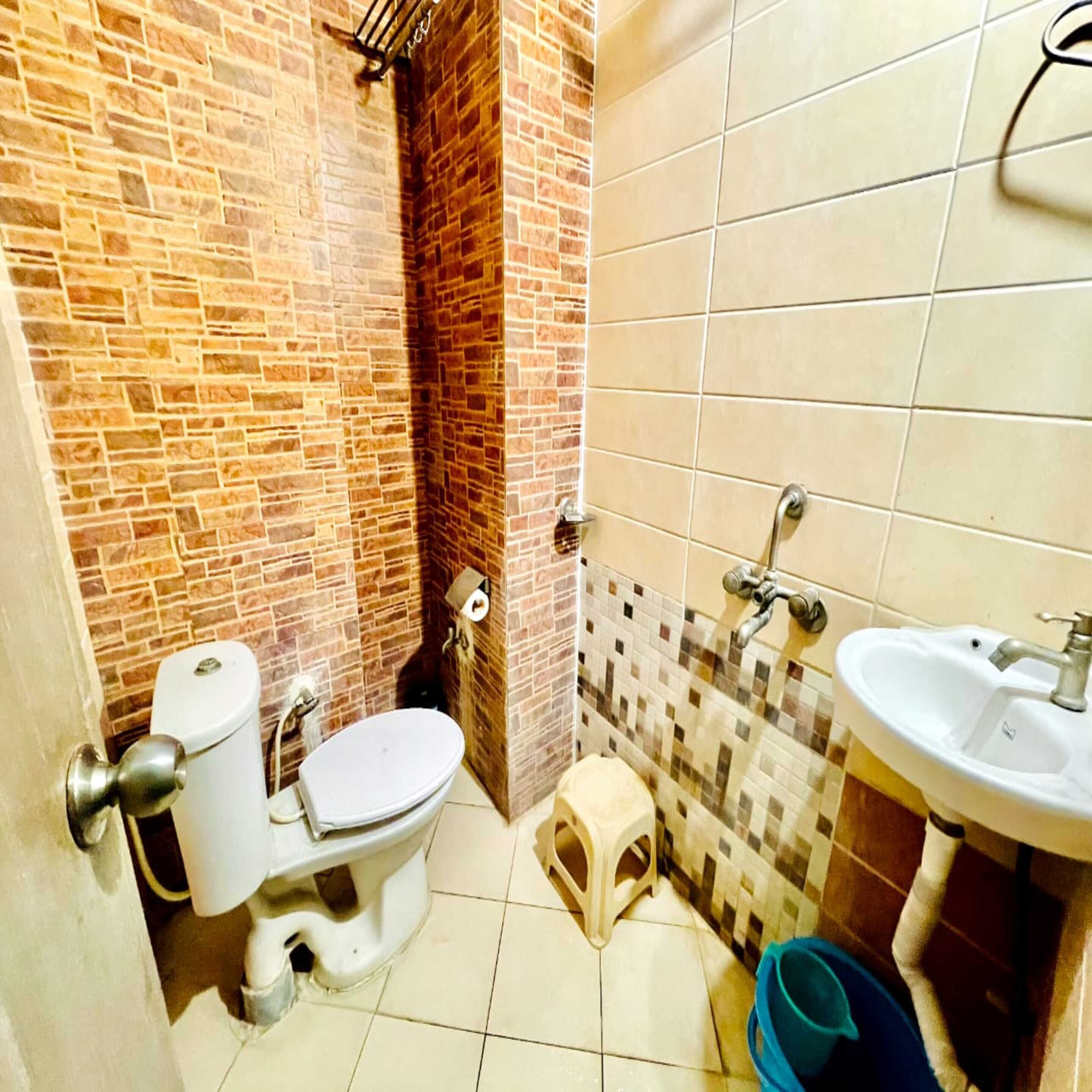 A small bathroom with a toilet, a sink, and a shower area.