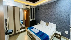A modern bedroom with a large bed, a ceiling fan, and a textured wall. - SKG Royal Palace (Bhopal)
