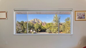A room with a large window offering a view of a mountain and trees. - Sedona Retreat with Red Rock Views, Mid-Century Charm | Upper Level Duplex (Sedona)