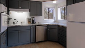 A modern kitchen with dark cabinets, a stainless steel dishwasher, and a window providing natural light. - Sedona Retreat with Red Rock Views, Mid-Century Charm | Upper Level Duplex (Sedona)