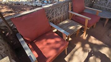 A patio area with two wooden chairs and a table, surrounded by a decorative stone wall.