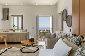 Relax in a serene space with a sofa, coffee table, and balcony overlooking the sea.