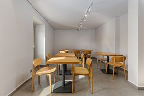 Experience a spacious room with a clean design, featuring tables and chairs for easy movement and interaction.