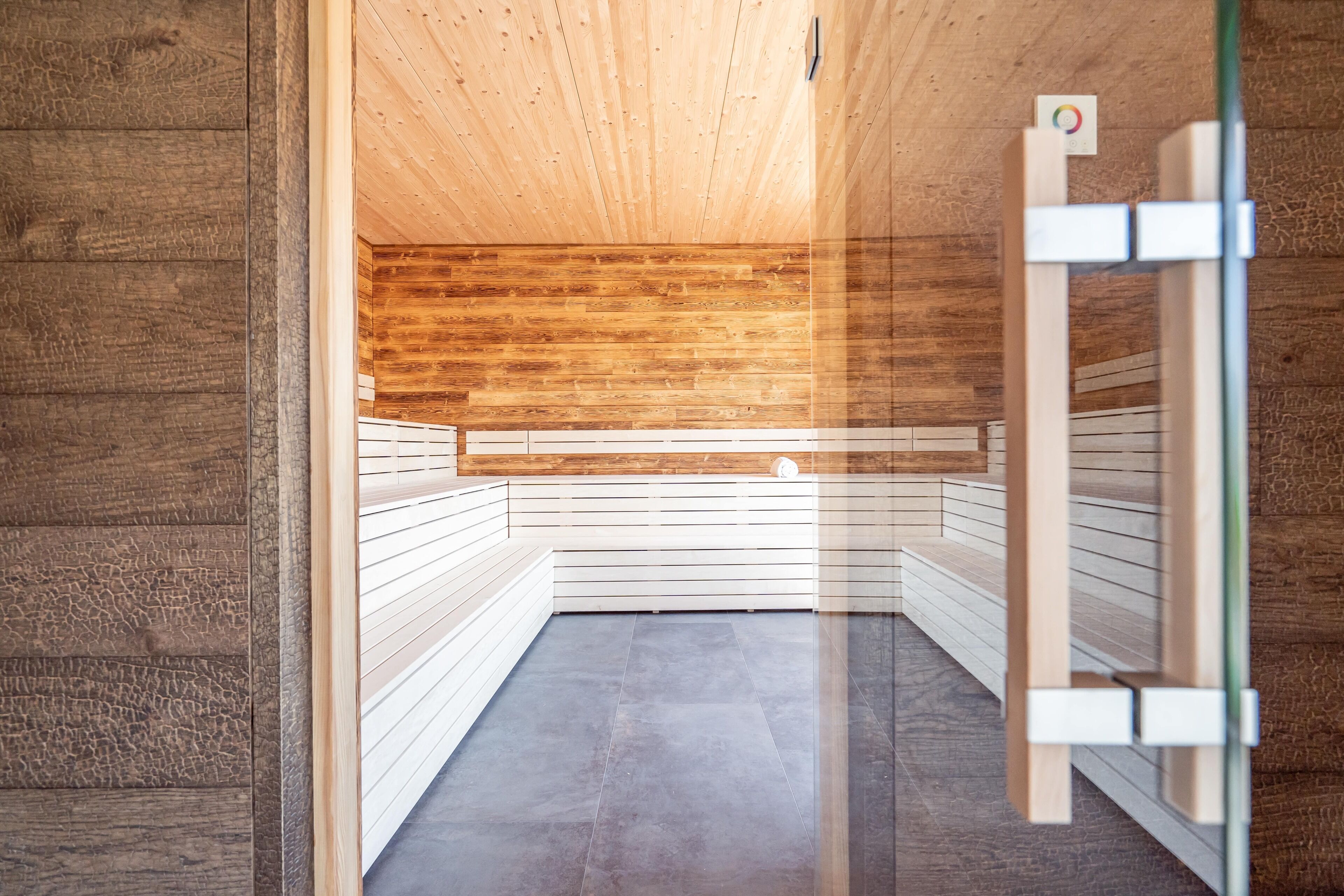 A sauna with wooden walls and benches, a tiled floor, and a wooden ceiling.