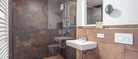 A modern bathroom with a glass-enclosed shower, a white sink, and a large mirror.