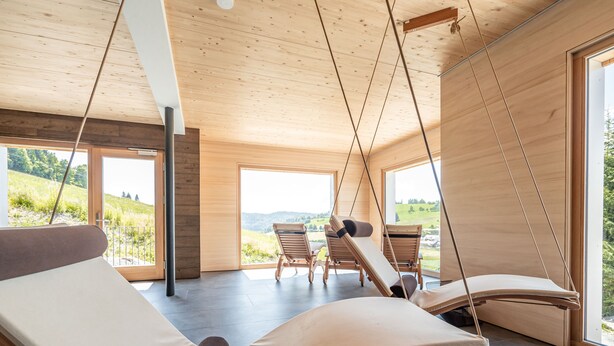 A modern interior with wooden ceiling beams, large windows, and a view of a green landscape. - stuub todtnauberg (Todtnau)