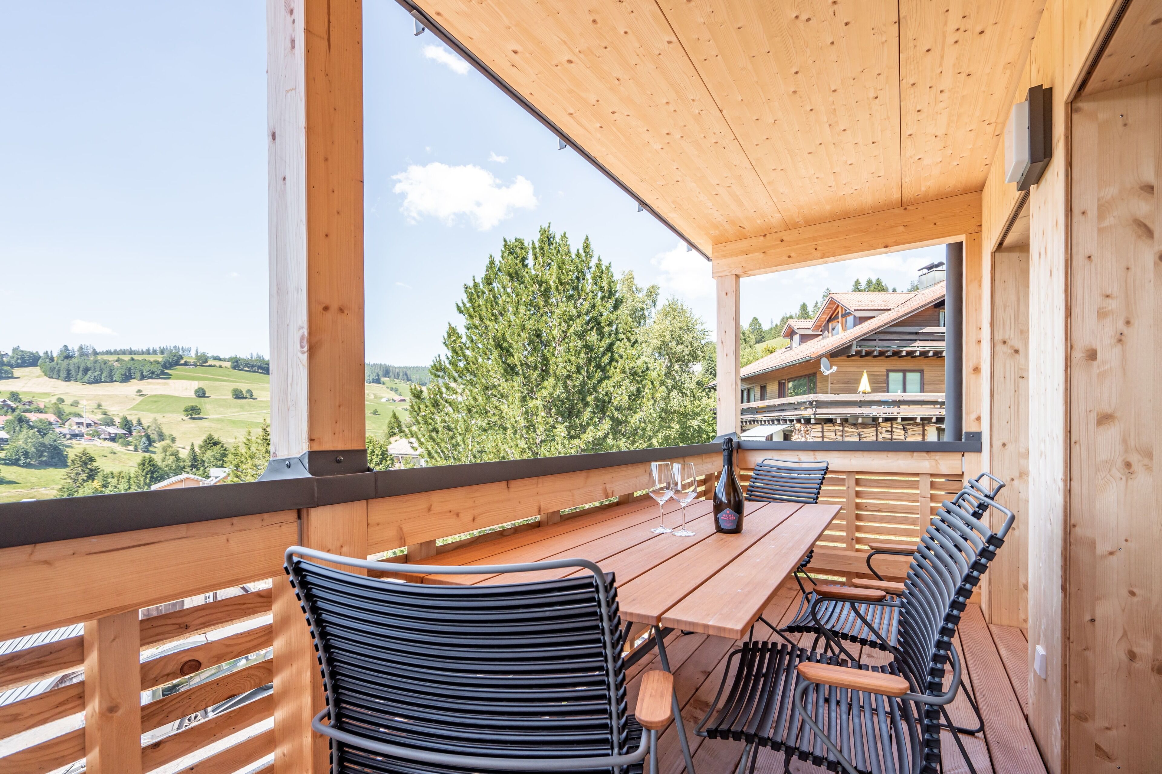Eine Holzterrasse mit Tisch und Stühlen mit Blick auf eine reizvolle Landschaft.