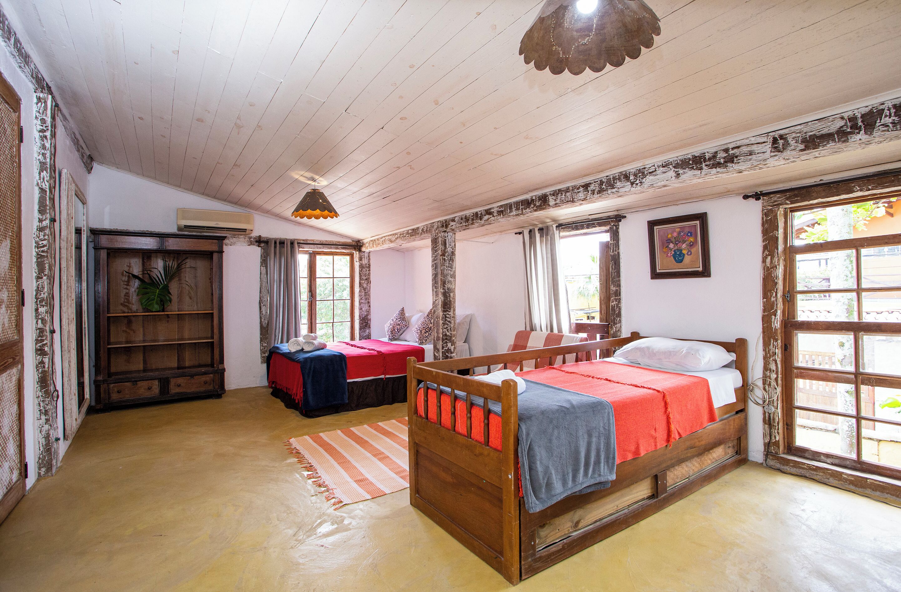 A room with a wooden bed, a small table, a sofa, and a window with a view.