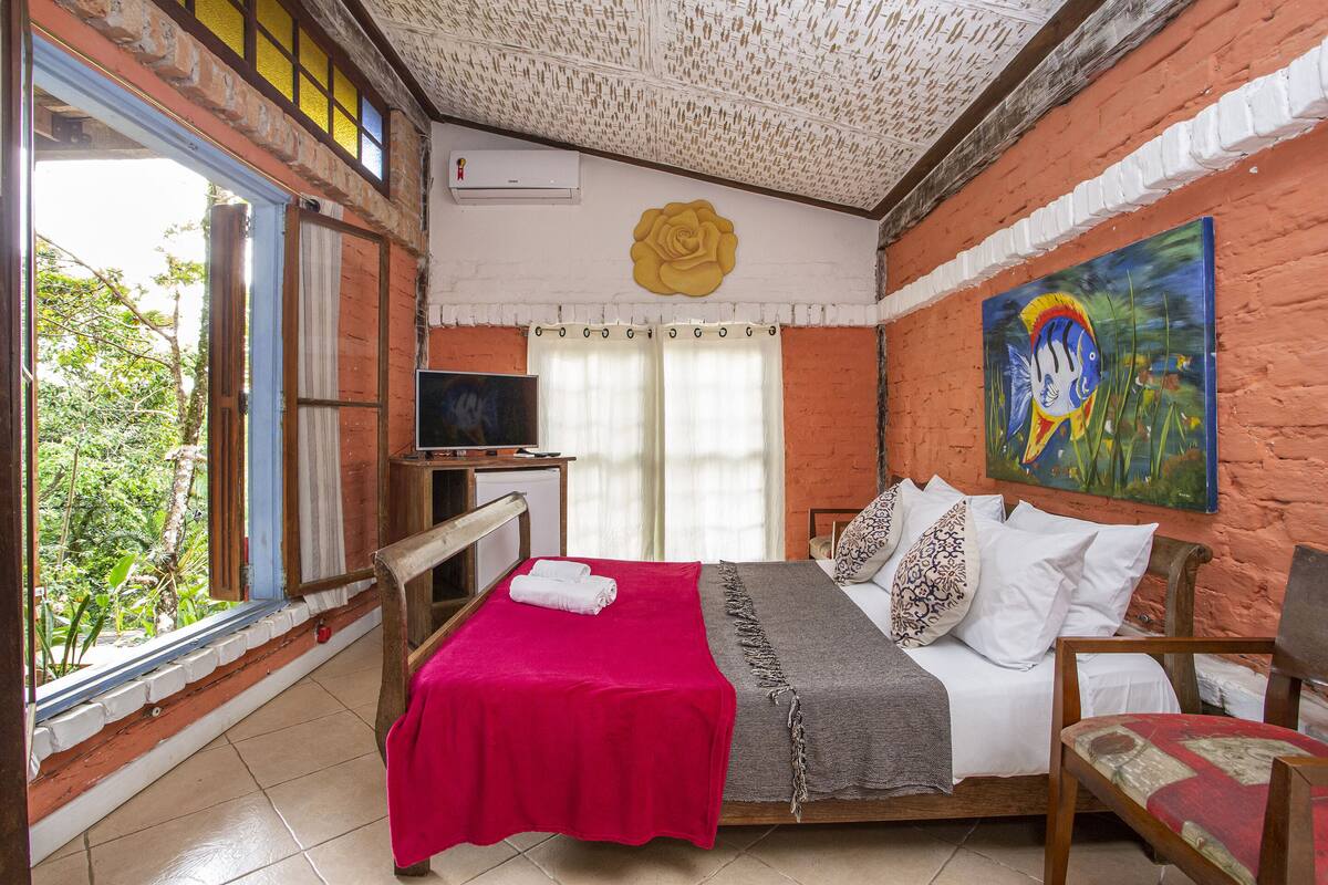 Une chambre à coucher avec un lit, une télévision, une fenêtre et un tableau au mur.