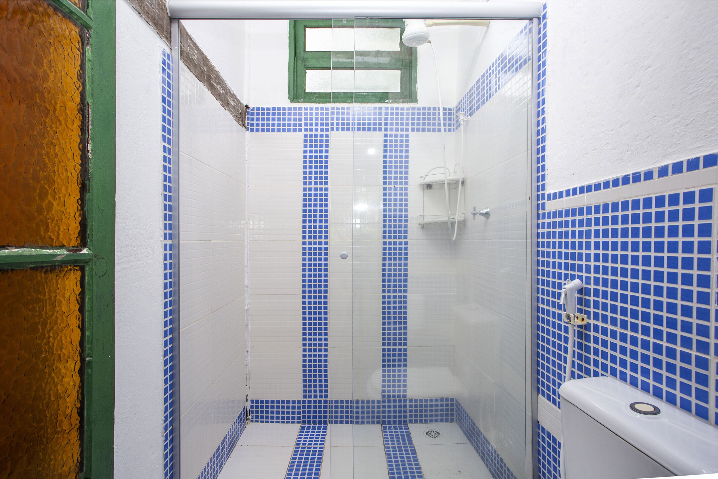 A bathroom with blue-tiled walls and a white toilet.
