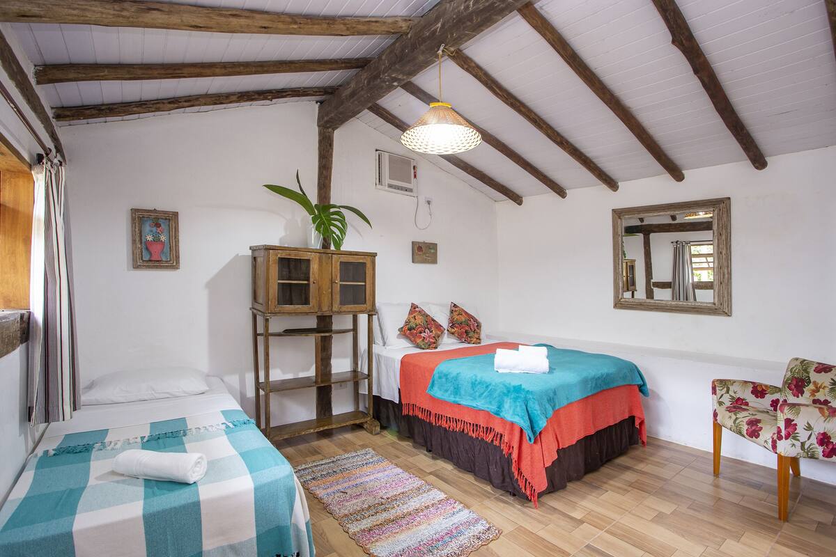 Une chambre avec deux lits, une armoire en bois, un miroir et une chaise.