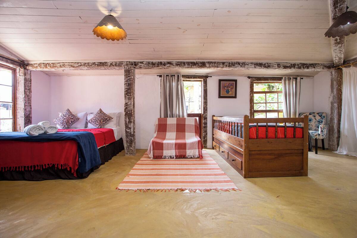 Une pièce comprenant un lit, une chaise, une armoire en bois et une fenêtre.