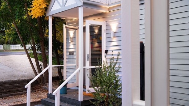 Uma casa com varanda, escadaria e um pequeno jardim.