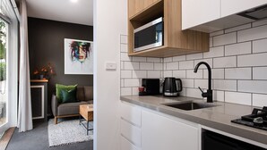 Cozinha moderna com azulejos brancos, uma torneira preta e um micro-ondas.