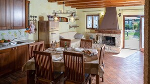 A rustic kitchen with wooden cabinets, a dining table set for four, and a stone fireplace. - Regarda - Countryhouse Nocino 1 in the middle of Lake Garda vineyards (Lazise)