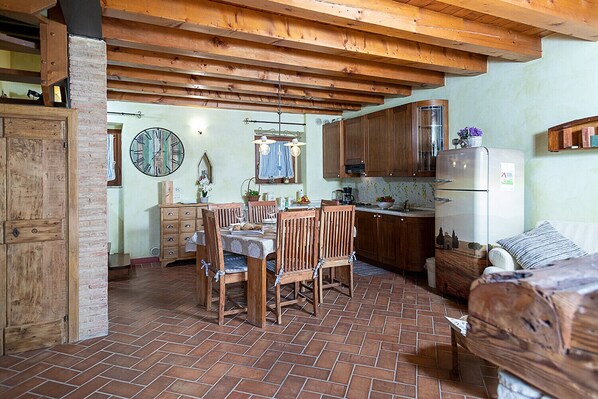 A rustic kitchen with wooden cabinets, a dining table with chairs, and a refrigerator.