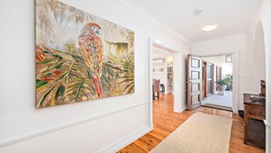A hallway with a large abstract painting, wooden flooring, and a rug. - Nelson Bay CBD Oasis - 13 Government Rd (Nelson Bay)