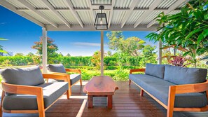 A covered outdoor seating area with wooden furniture and a view of a lush garden. - Nelson Bay CBD Oasis - 13 Government Rd (Nelson Bay)