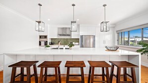 A modern kitchen with a large island, stainless steel appliances, and a view of the city. - Nelson Bay CBD Oasis - 13 Government Rd (Nelson Bay)