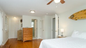 A bedroom with a bed, wooden dresser, and a ceiling fan. - Historic charm blended with modern convenience! (Wrightsville Beach)