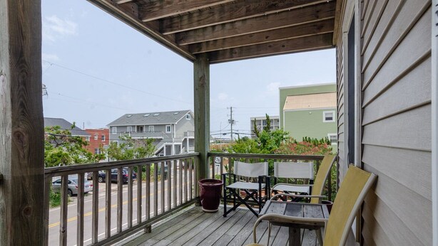 A wooden porch with a railing, a table, and two chairs. - Historic charm blended with modern convenience! (Wrightsville Beach)