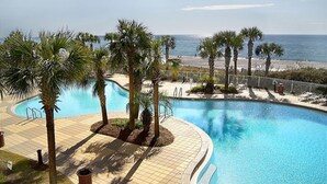 Ett poolområde med palmer och utsikt över stranden.