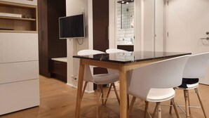 Et moderne køkken med spiseplads, hvide skabe, et fladskærms-TV og en indbygget bruser.