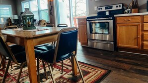 Une cuisine dotée de meubles en bois, d’un four en acier inoxydable et d’un coin repas avec une table et des chaises.