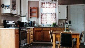 Une cuisine avec des meubles de rangement en bois, une cuisinière, un évier et une table à manger avec des chaises.